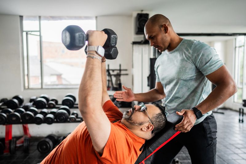 Fitness instructor helping student to do supine at gym