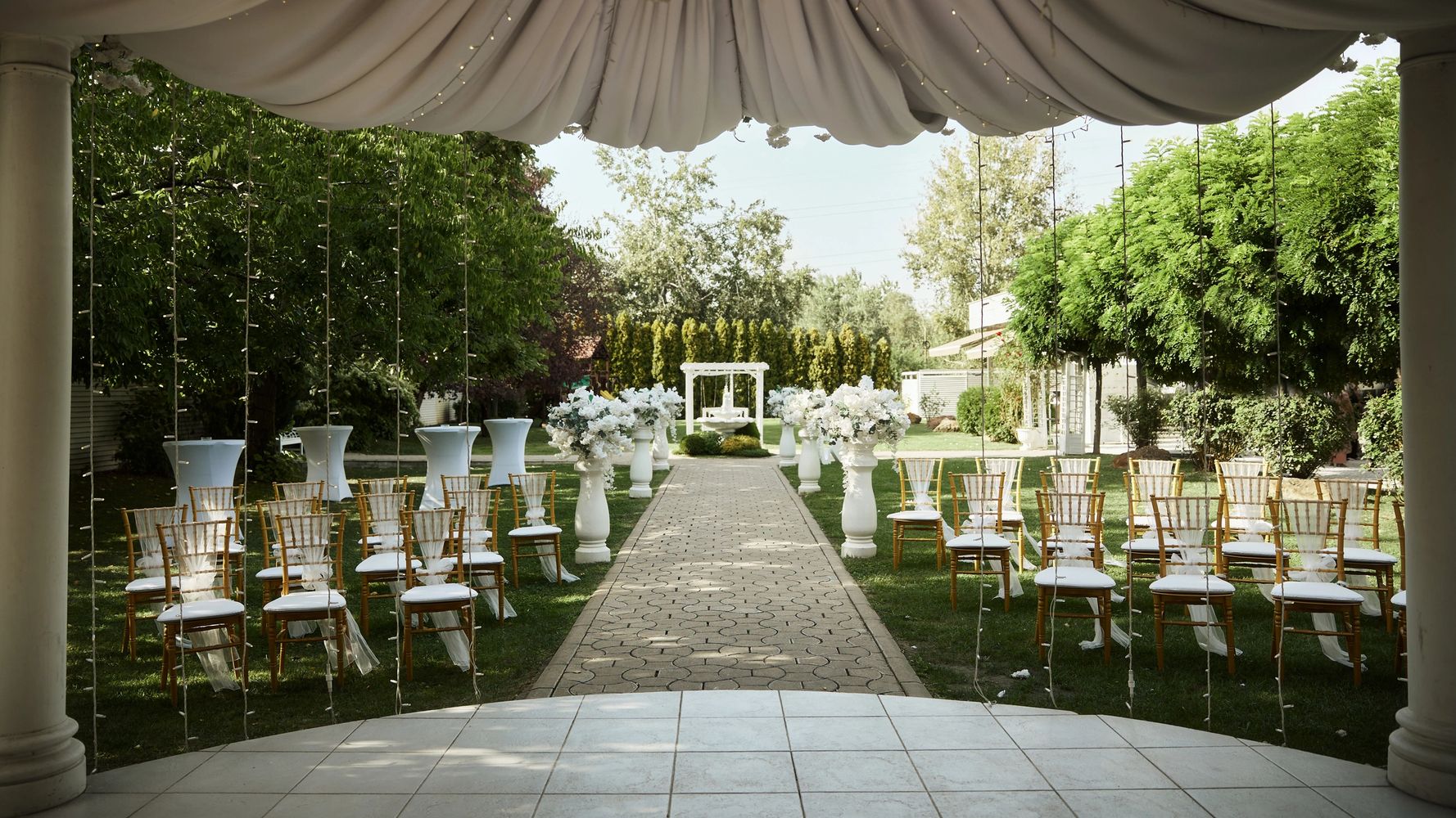 Elegant outdoor wedding setup with chairs, flowers, and a canopy.