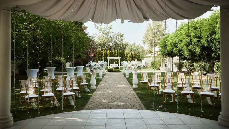 Photo of Beautiful Wedding Act Decoration With Large Flower Vases And Sphere Canopy Backyard.