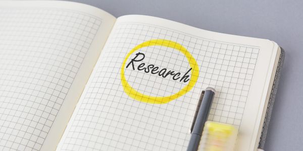 Notebook page with "Research" circled in yellow and a pen.