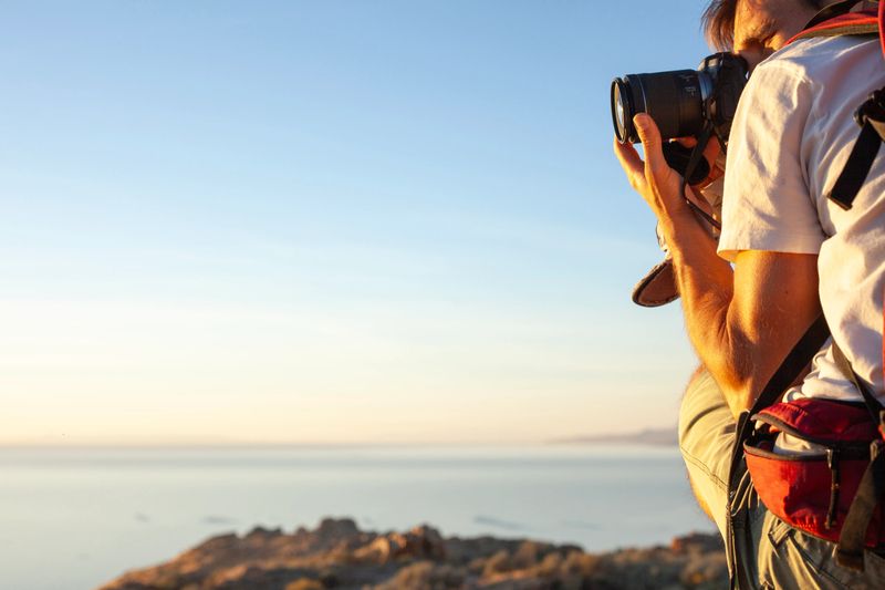 Profile view of man photographing in arid climate above salt lake, Antelope Island State Park, Utah