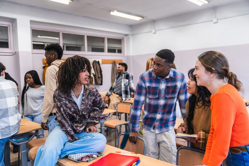 Diverse group of high school students working together on a project, discussing ideas and sharing knowledge in a classroom setting
