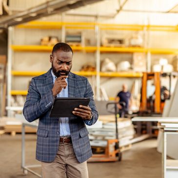 Man in a blazer using a tablet in an industrial setting.