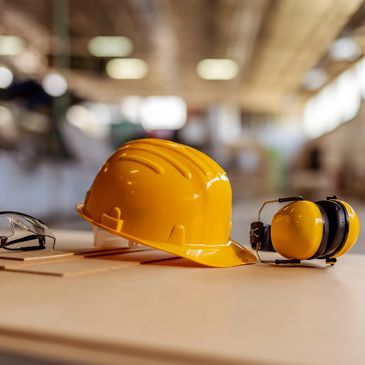 Yellow hard hat and earmuffs on a table.
