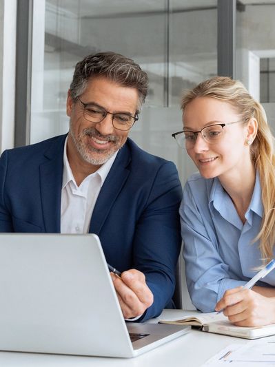 Two professionals discussing work while looking at a laptop.