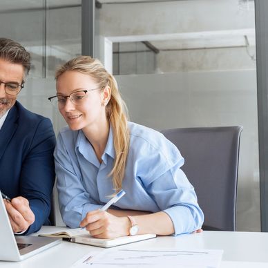 Two colleagues collaborating over a laptop in a modern office.