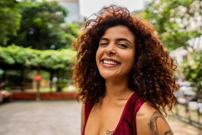 Jeune femme souriante aux cheveux bouclés en extérieur.