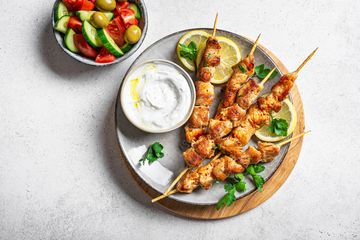 Grilled chicken skewers with dipping sauce and fresh salad on the side.