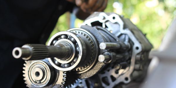 Close-up of a mechanical gear assembly with a person working in the background.