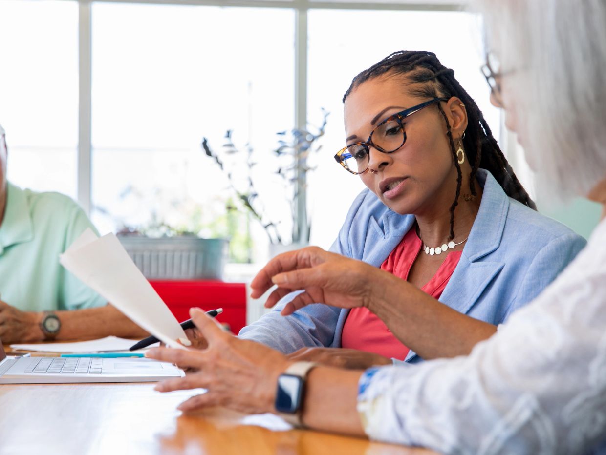 Two women discussing documents during a meeting in a bright office.