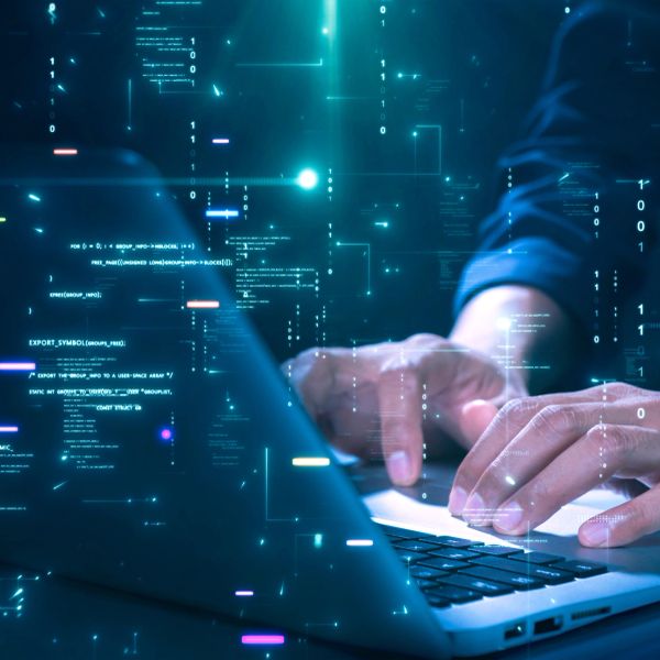 Person typing on laptop with digital code overlay, representing cybersecurity or programming.