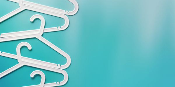 percheros de plástico blancos en un fondo sólido color celeste.