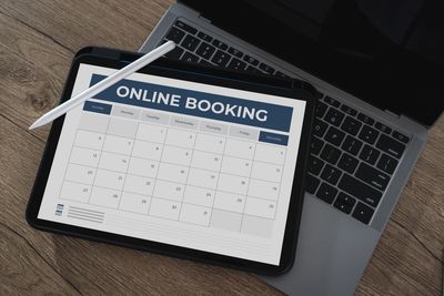 Tablet showing an online booking calendar on a laptop keyboard.
