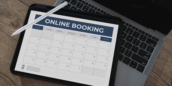 Tablet displaying an online booking calendar on a laptop keyboard.