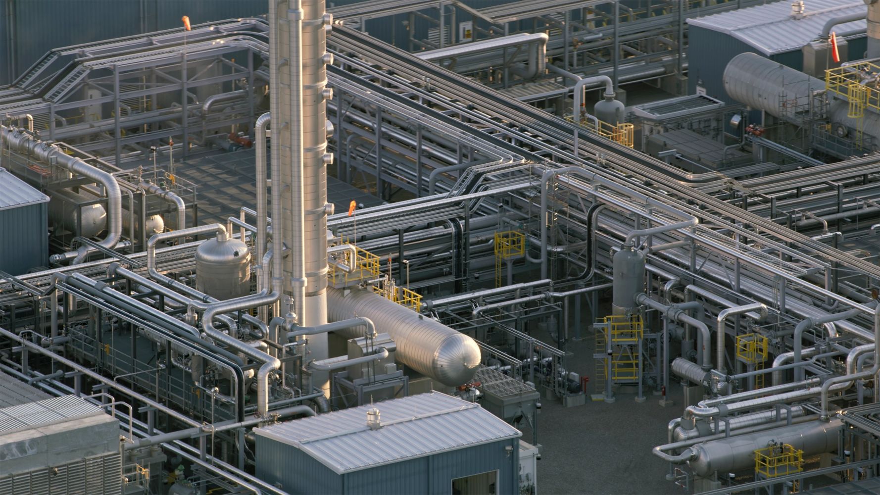 A complex network of metallic pipes and industrial equipment at a refinery.