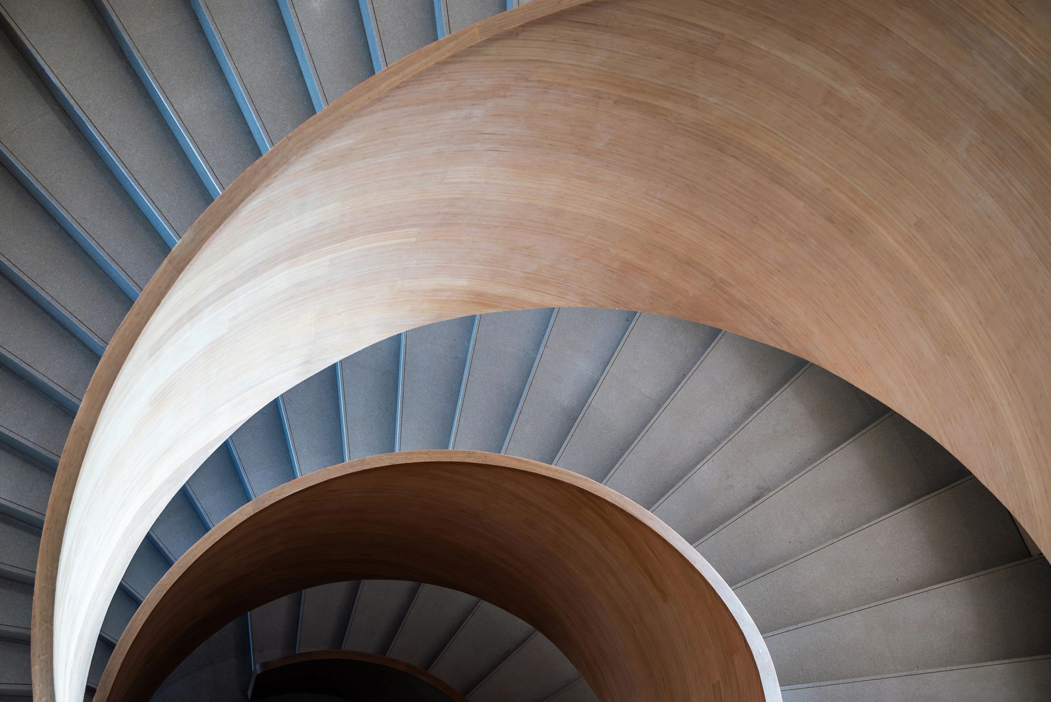 Top view of a modern spiral staircase with wooden handrail.