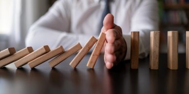 Hand stopping falling dominoes.