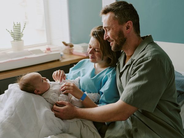Happy parents lovingly holding their newborn baby in a cozy room.