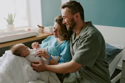 Parents lovingly holding their newborn baby in a hospital bed.