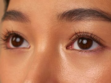 Close-up of brown eyes with natural makeup and long lashes.