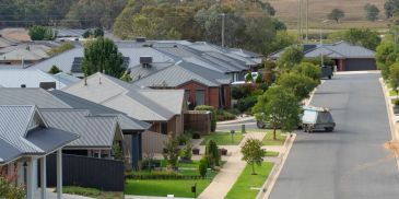 Suburban street with single-story houses and green lawns.