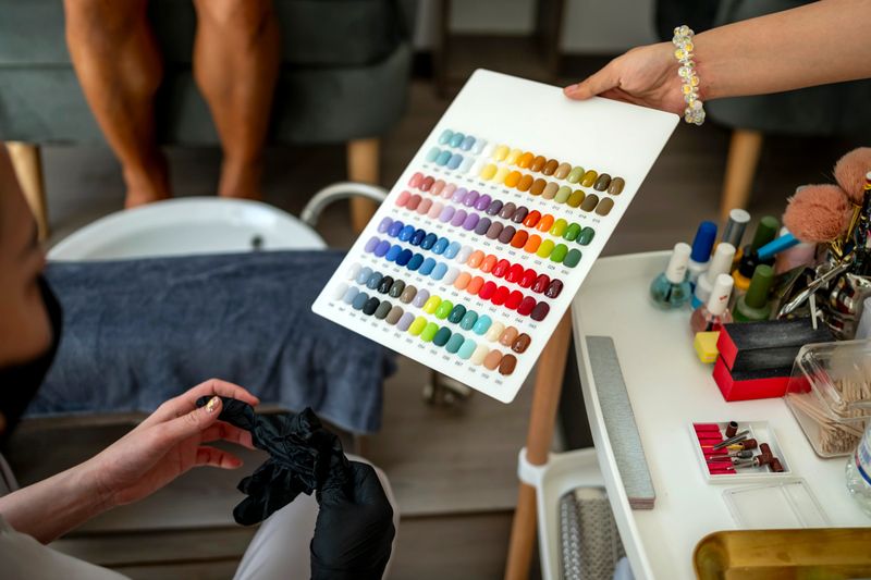 A nail technician displays an extensive color palette to a client in a modern salon setting, highlighting various manicure options.