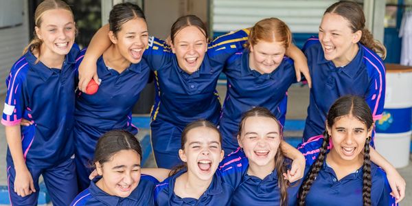 A joyful group of girls in blue sports uniforms laughing together.
