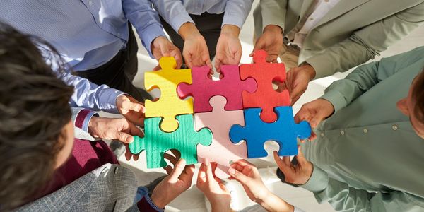 People collaborating to assemble a colorful puzzle together.
