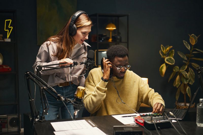 Young people in headphones recording podcast in team in studio