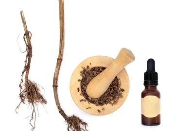 Dried roots, crushed herbs in a mortar, and a dropper bottle for herbal medicine.