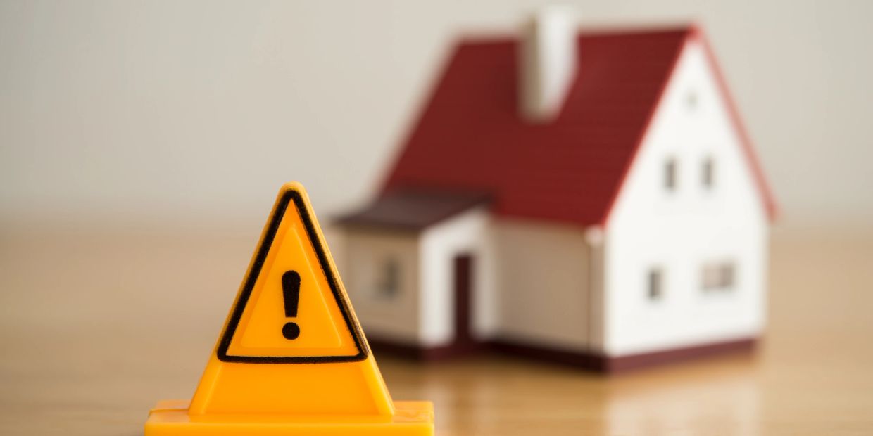 Warning sign in front of a house model.