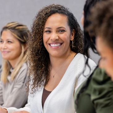 Smiling woman with curly hair in a meeting with colleagues.