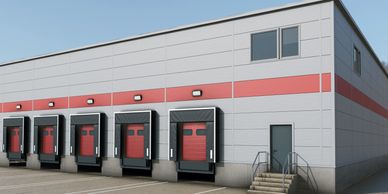 Modern warehouse with multiple loading docks and a side entrance door.