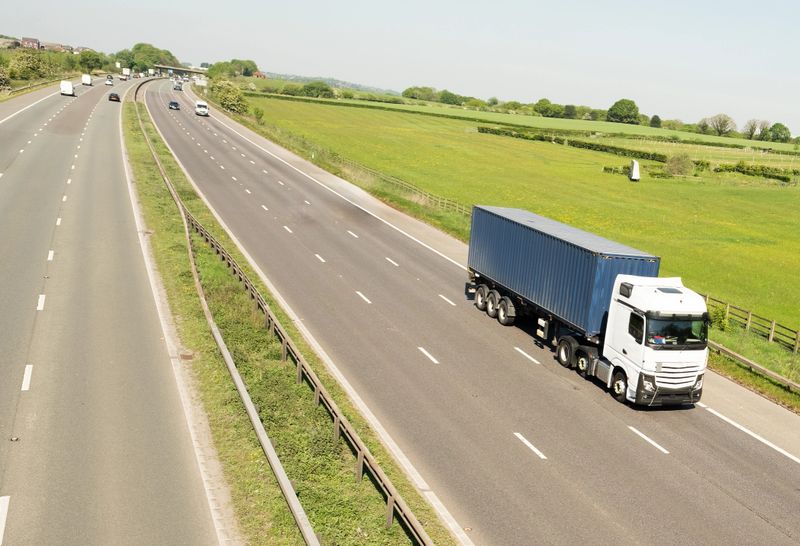 Three axle LGV towing three axle trailer in lane one of UK motorway and heading south in the Spring.