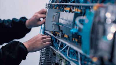 Person working on a server rack with network cables.