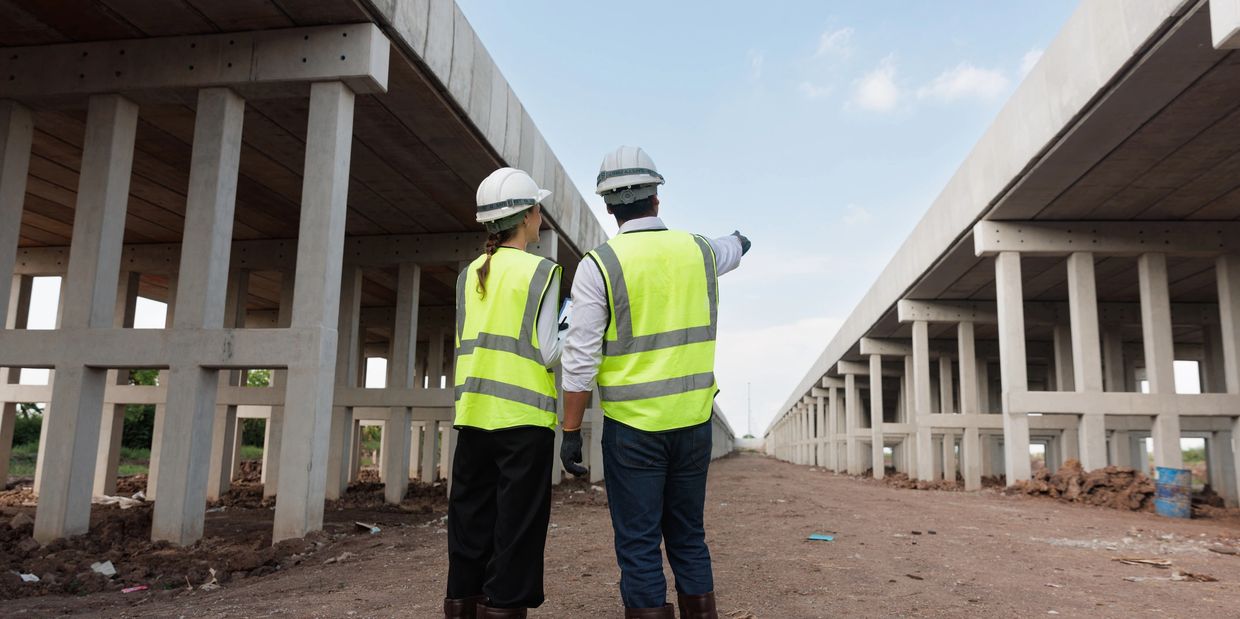 Two construction workers inspecting a bridge under construction.