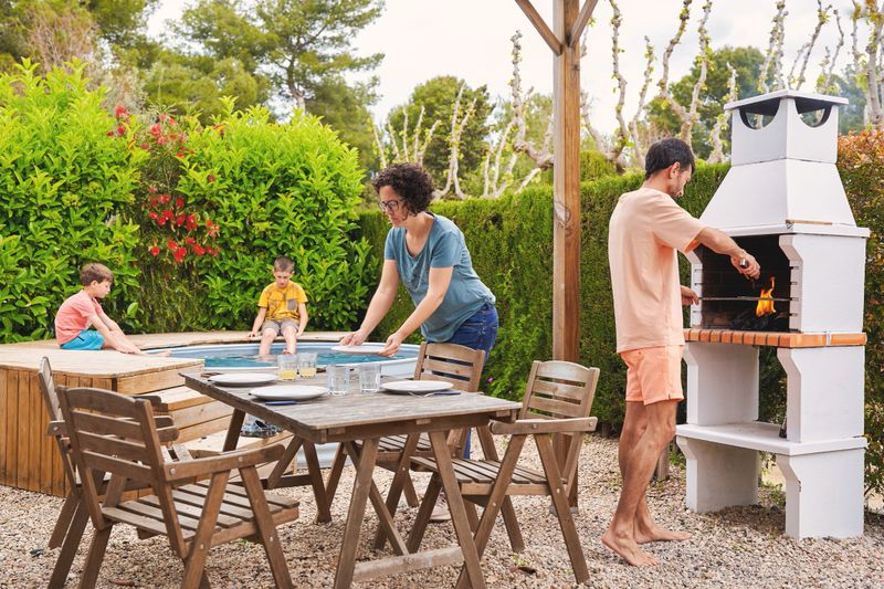 Family enjoying summer day with barbecue and pool at home