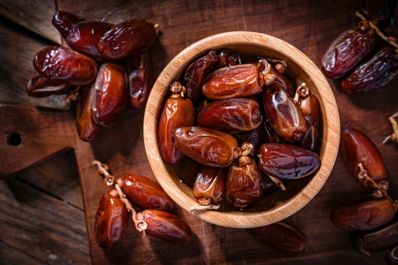 Overhead view of organic dried dates in a wooden bowl