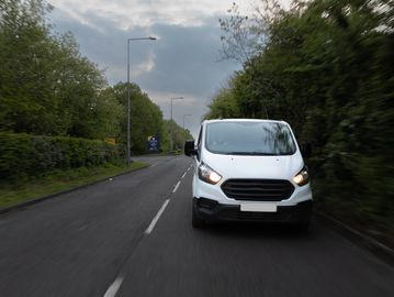White van driving on a suburban road.