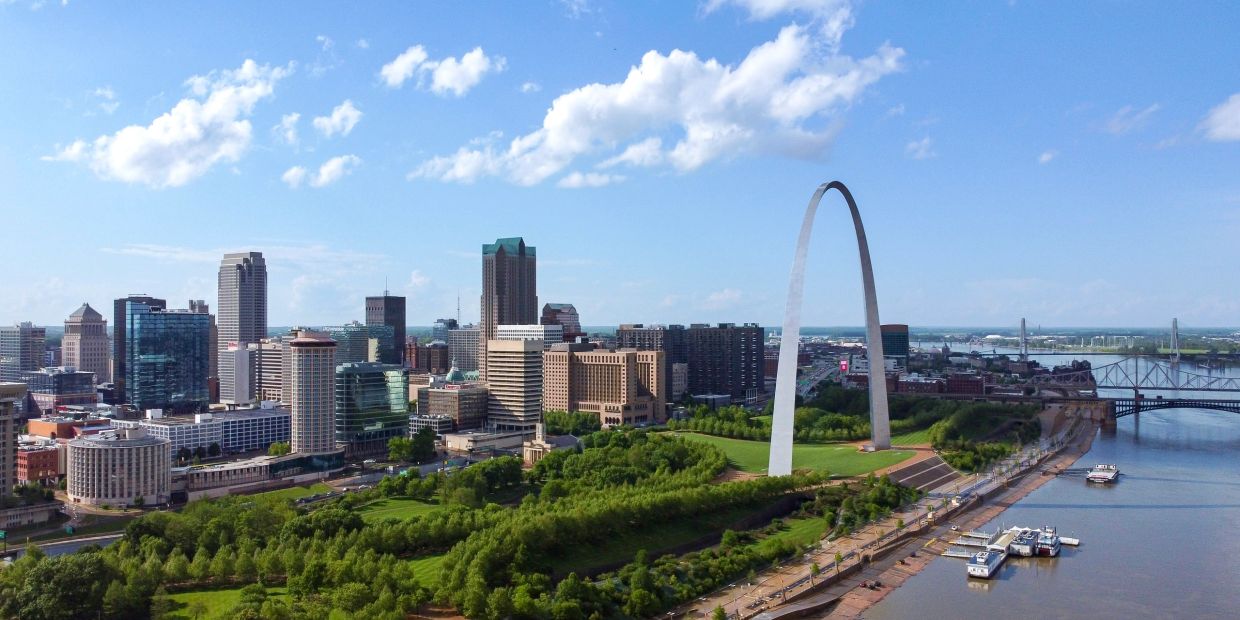 City skyline with iconic Gateway Arch and river.