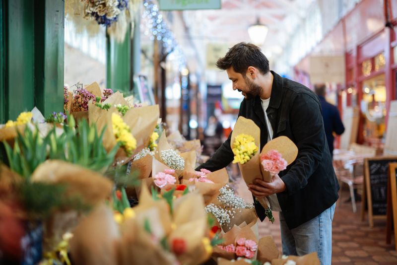 Young man in a flower shop and choosing flowers. The concept of gardening and flowers. Male customer looking at potted aloe plant, shopping at home goods store, copy space