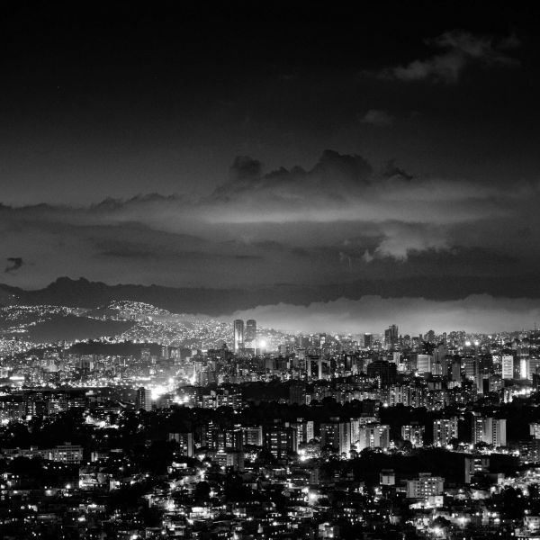 Black and white night cityscape with lights and clouds.