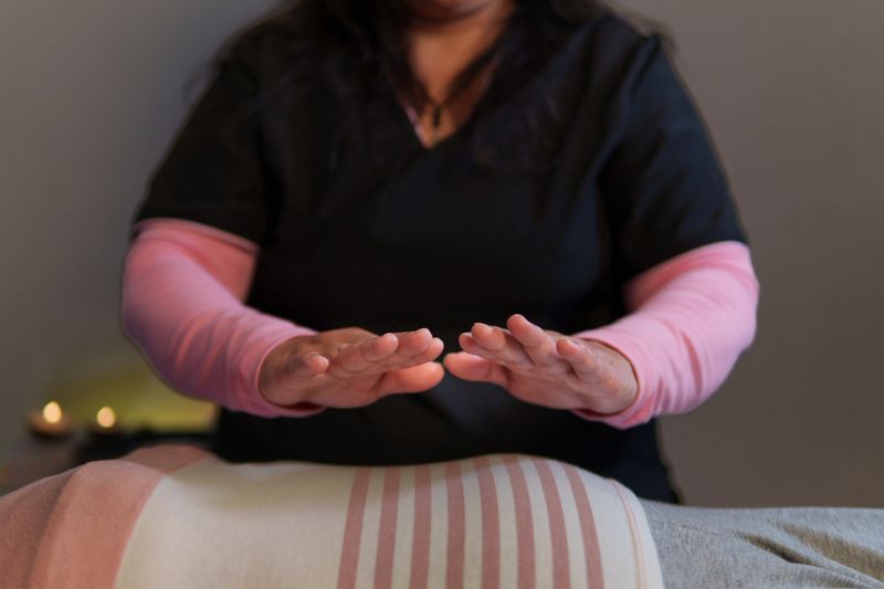 Reiki master channeling energy to patient lying on massage table, promoting relaxation and well-being