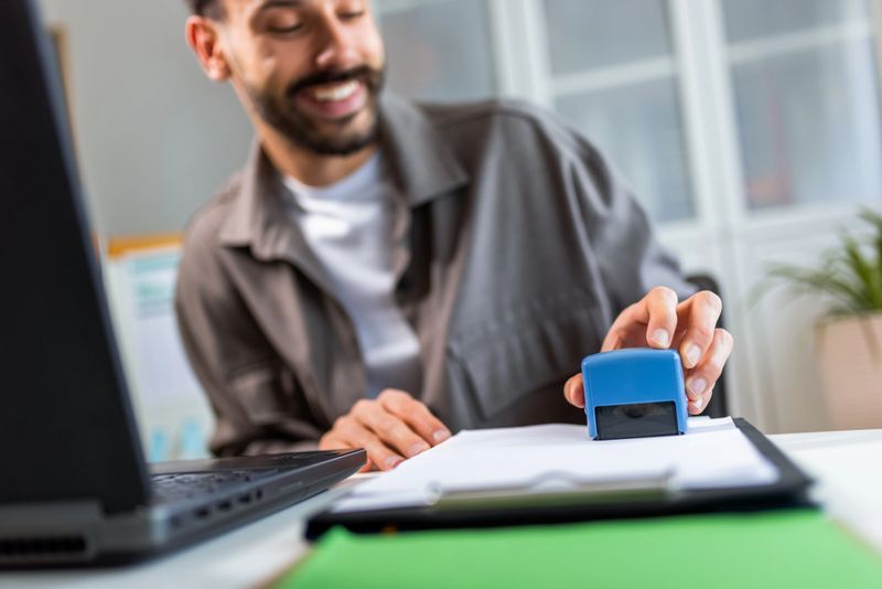 A man stamping or sealing a document with a rubber stamp. This image symbolizes the completion of a task, official approval, or finalizing business matters.