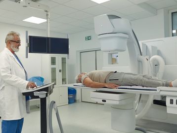 Doctor operates medical imaging machine for patient scan.