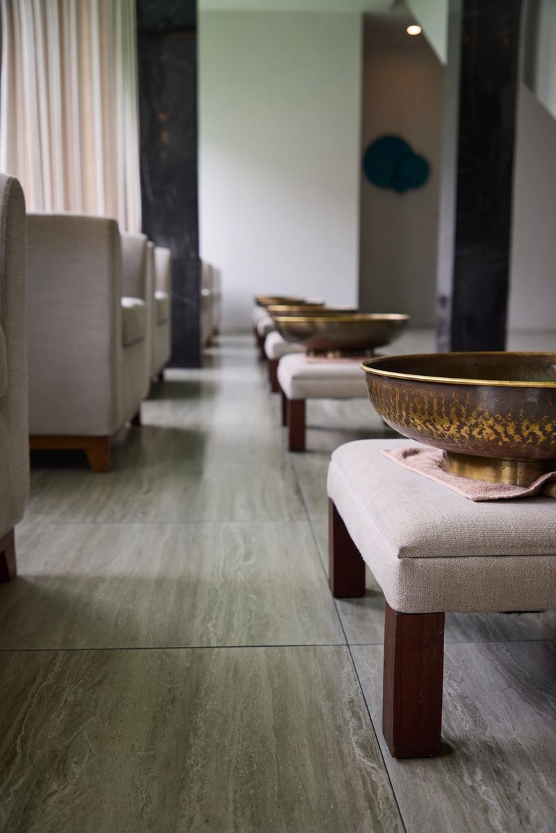 Modern spa interior featuring rows of plush chairs and decorative brass bowls on stools, evoking a serene and relaxing atmosphere ideal for therapeutic treatments or relaxation spaces in wellness facilities.