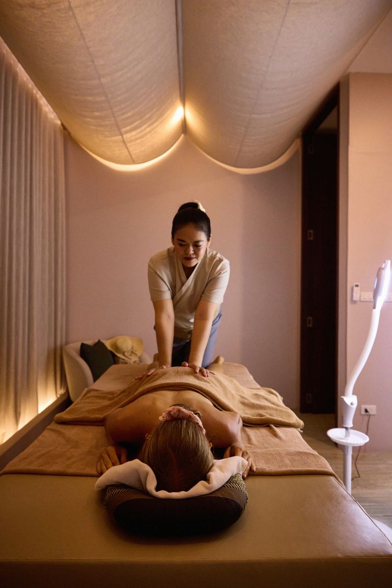 A massage therapist performs relaxation techniques on a client lying on a table, evoking feelings of calm and wellness. The serene spa ambiance accentuates peace and rejuvenation in the dimly lit space.