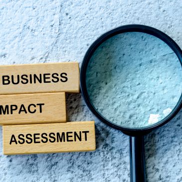 Wooden blocks with 'Business Impact Assessment' and a magnifying glass.