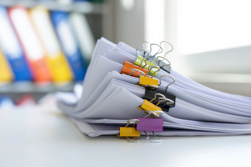 Stack of report paper files in business office clipped with clips
