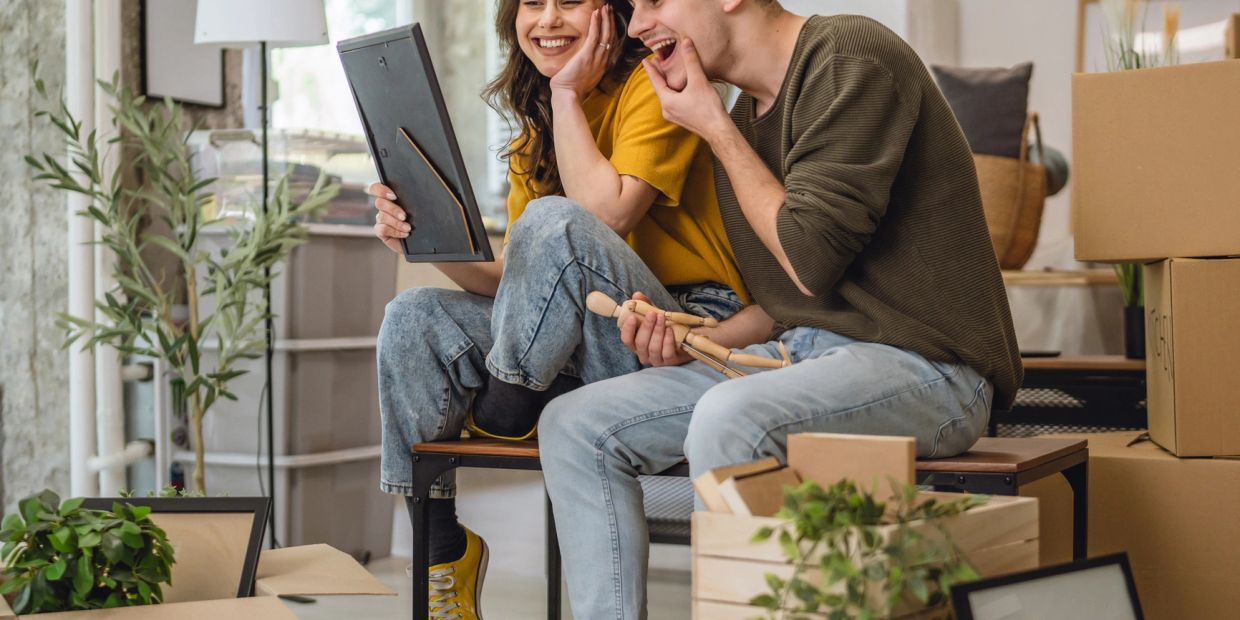 Happy couple looking at a photo frame surrounded by moving boxes.